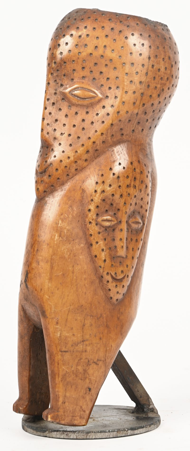 Een Afrikaans beeld gemaakt uit been, een geperforeerd hoofd met aan weerskanten van het lichaam een geperforeerd masker.