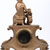 Een tafelpendule in bronslook met daarop een beeld van moeder en kind.