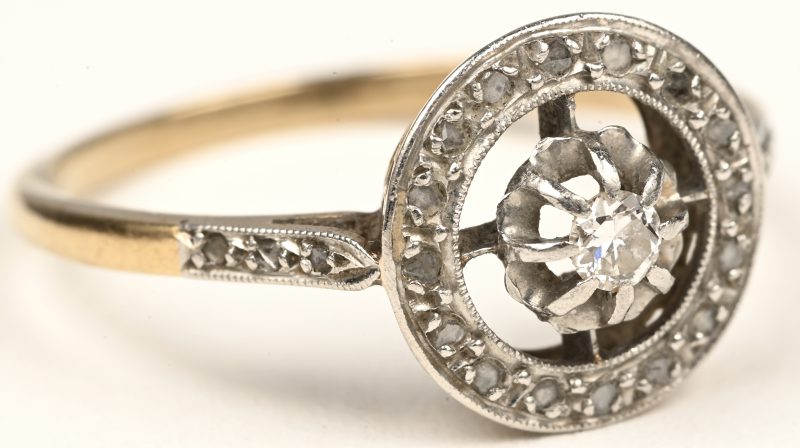 Een 18 karaats witgouden ring bezet met één centrale briljant van +- 0,10 ct. en diamanten oude slijp met een gezamenlijk gewicht van +- 0,20 ct.