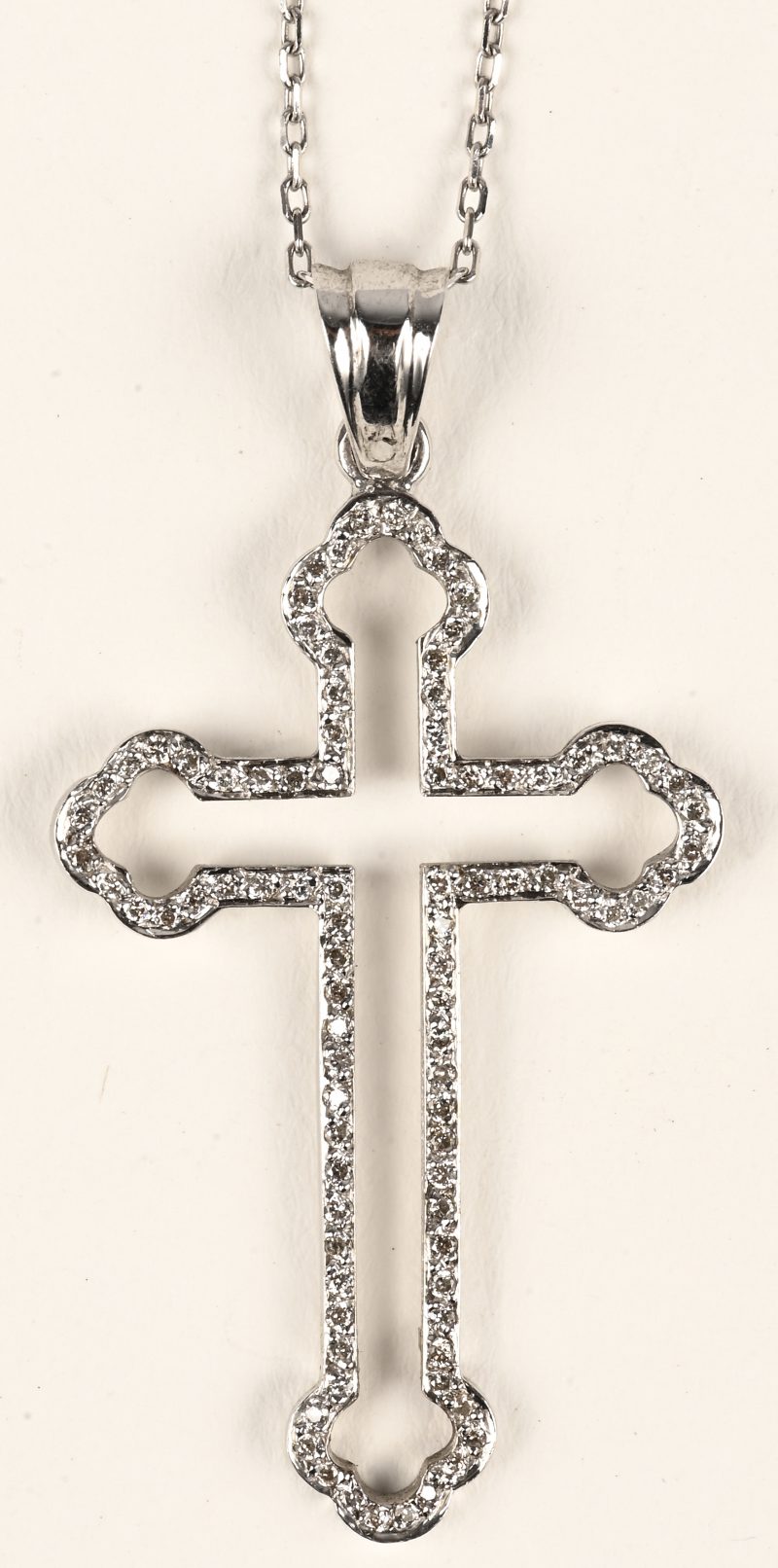 Een 18 karaats witgouden halsketting met hanger in de vorm van een kruis bezet met briljanten met een gezamenlijk gewicht van +- 0,28 ct.