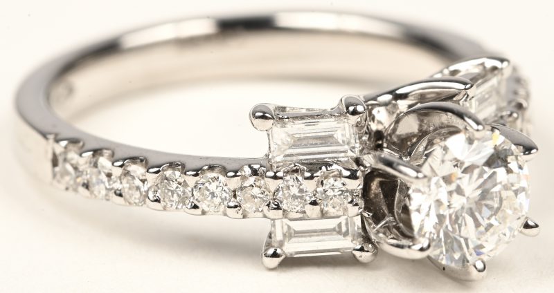 Een 18 karaats witgouden ring bezet met een centrale briljant van +- 0,58 ct.  briljanten en diamant baguetten van +- 0,56 ct.