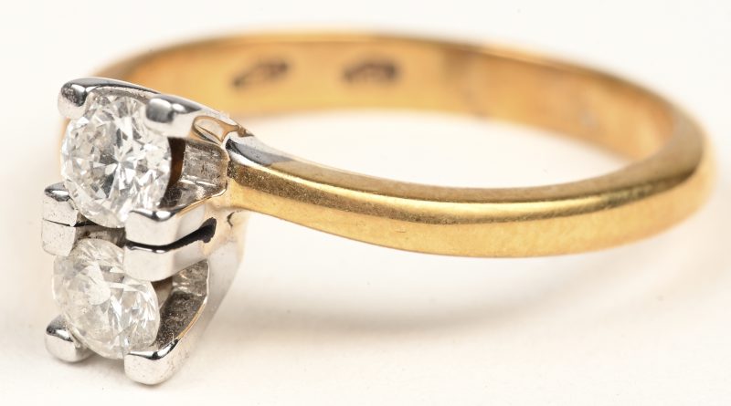 Een 18 karaats wit en geelgouden ring bezet met twee briljanten met een gezamenlijk gewicht van +- 0,52 ct.
