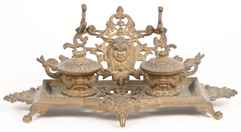 Een brons gesculpteerde inkthouder met leeuwenkop en twee potjes.