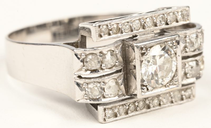 Een 18 karaats witgouden art deco ring bezet met 24 diamanten oude slijp met een gezamenlijk gewicht van +- 0,44 ct. en een centrale briljant van +- 0,60 ct.