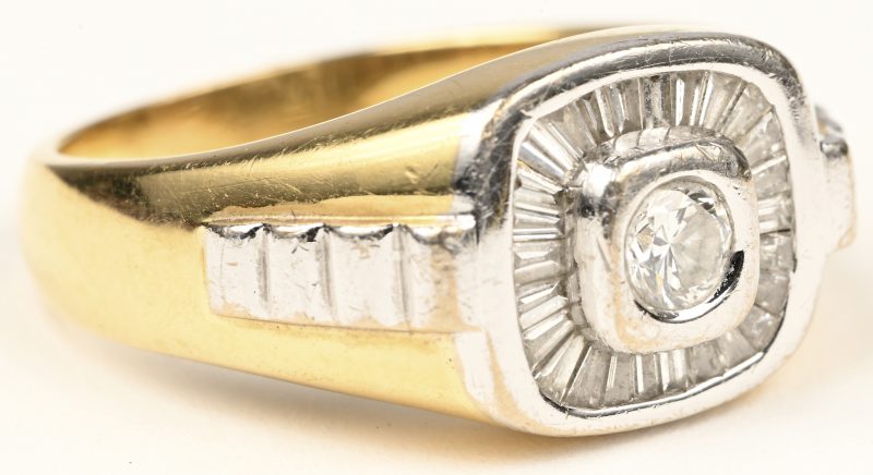 Een 18 karaats wit en geelgouden ring bezet met een centrale briljant van +- 0,20 ct. en diamant baguetten met een gezamenlijk gewicht van +- 0,50 ct.