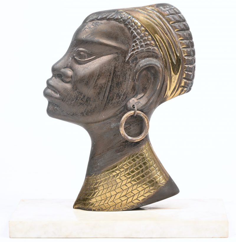Een hoofd van een Afrikaanse dame in koper, gemonteerd op een marmeren sokkel.