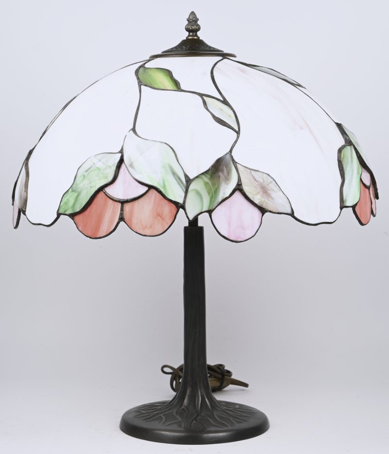 Een tafellamp in tiffany stijl met een voet voorstellend een boomstam met wortels en een florale kap.