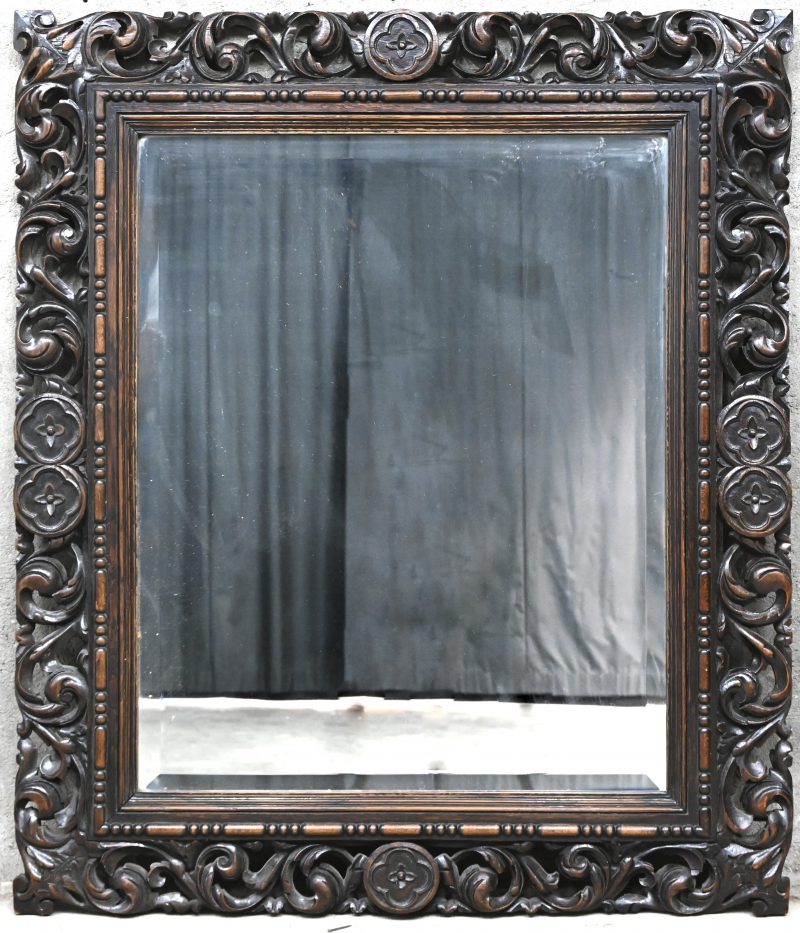 Een spiegel met gebeeldhouwd houten lijst.