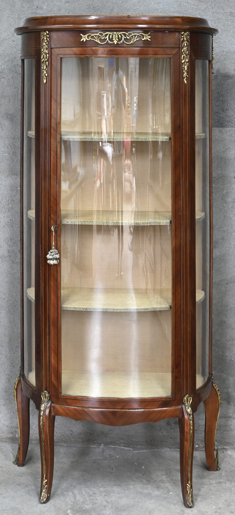Een houten vitrinekast, 1 deurs met 2 glazen zijden. Vergulde messing ornamenten.