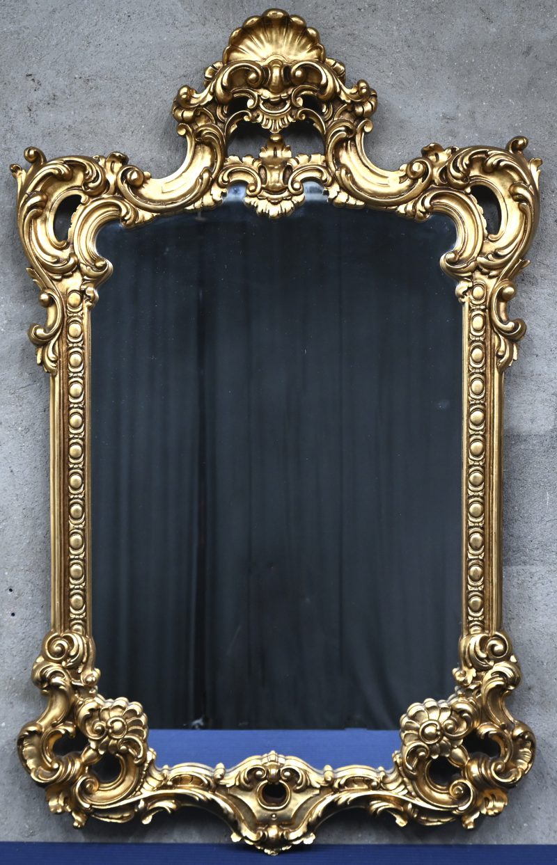 Een spiegel in verguld houten gesculpteerd kader.