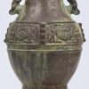 Een brons gesculpteerde vaas met Aziatisch decor. Bodemloos op houten sokkel.