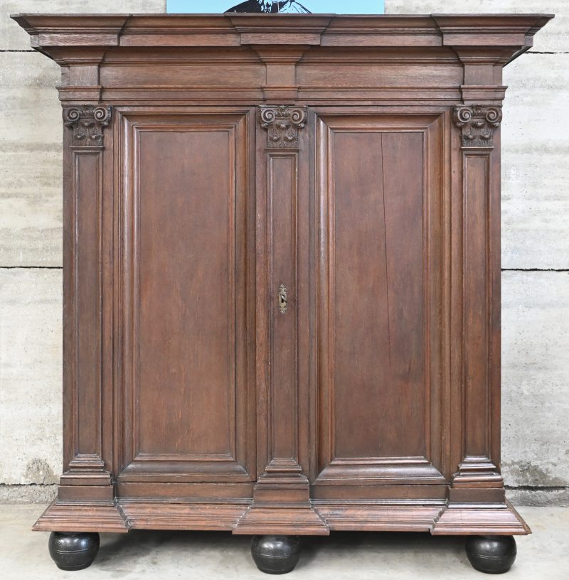 Een 19e eeuwse massief eiken Brugse kapiteelkast met 2 deuren en gesneden elementen.