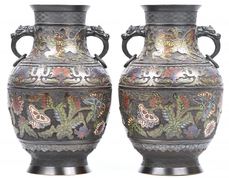 Een paar vazen van champslevé brons versierd met veelkleurige plantenmotieven op de buik en dito fabeldieren op de hals. Oren in de vorm van drakenkoppen met ringen. Onderaan gemerkt.