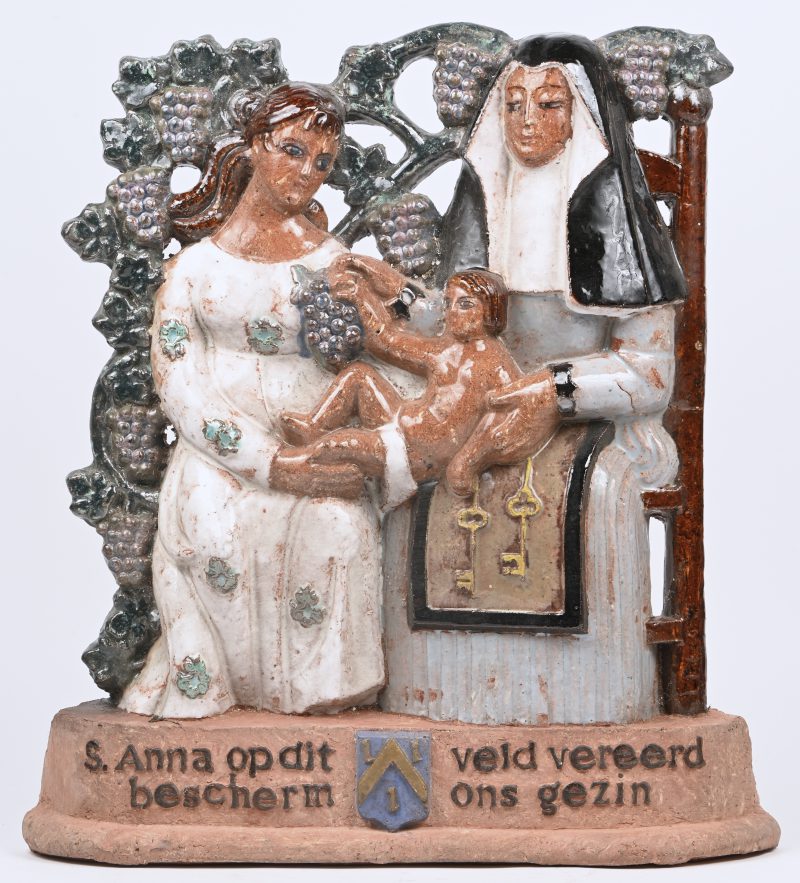 “Sint-Anna ten Drieën”. Een hoogreliëf van terracotta met veelkleurig glazuur. Met opschrift: “ S. Anna op dit Veld vereerd bescherm ons gezin. Achteraan gesigneerd en gedateerd 25/12/1954.