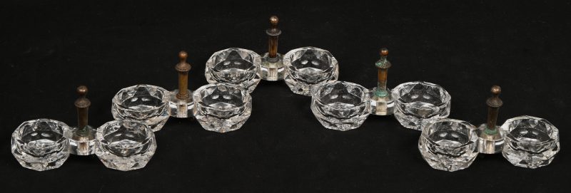 Een serie van vijf dubbele zoutvaatjes van kleurloos geslepen kristal met bronzen handvaatjes.