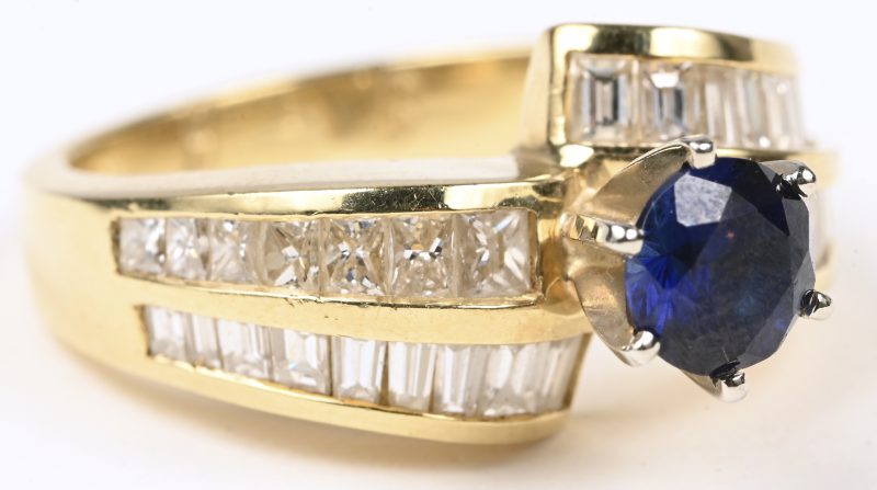 Een 18 karaats geel gouden ring bezet met diamantbaguetten en princesses met een gezamenlijk gewicht van ± 1 ct. en een centrale saffier van ± 0,70 ct.