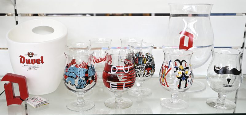 Een lot van 9 designer Duvel glazen, waarvan een 3 liter glas in originele doos, 8 glazen van verschillende ontwerpers, een plastic ijsemmer en een ontkurker in de vorm van de Duvel D.