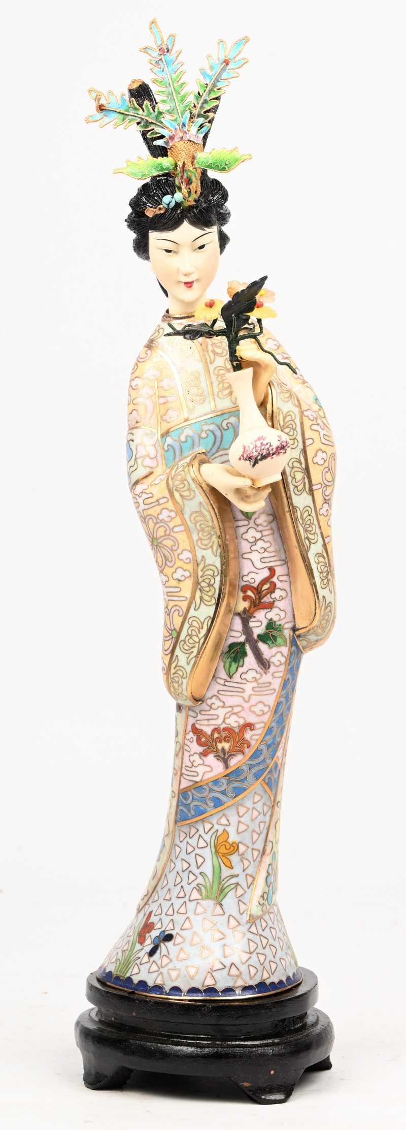 Een cloisonné beeldje van een Geisha met bloem en vaas in hand. Op houten sokkel, in kistje.