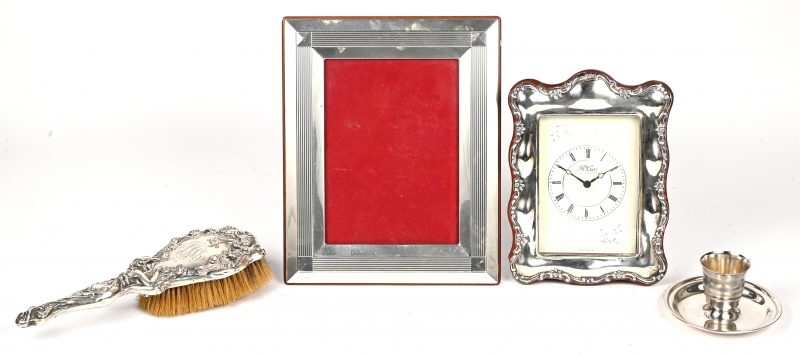 Een varia lot van 4 zilveren items bestaande uit een klokje, fotokadertje, handborstel en eihoudertje. Divers promille +800.