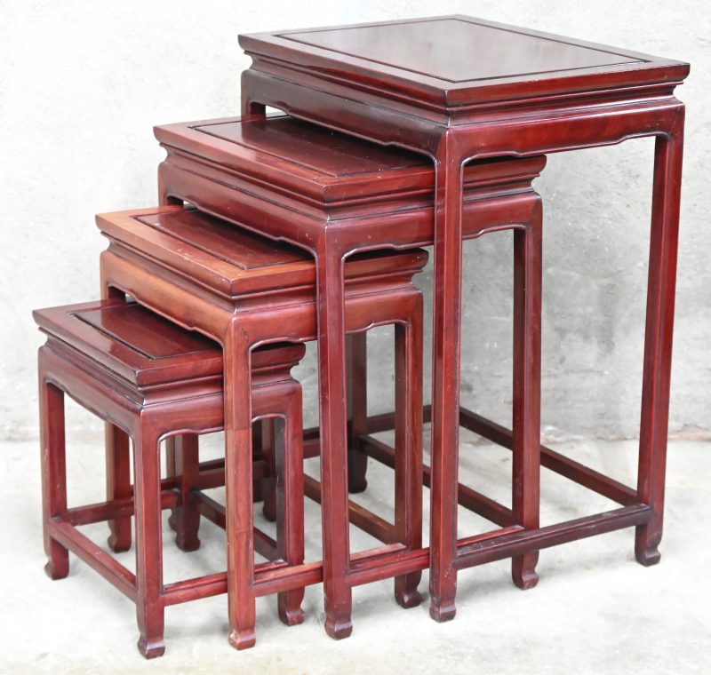 Een set van 4 Chinese rood gepatineerde houten bijzettafeltjes.