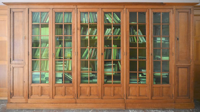 Een notenhouten boekenkast met 6 deuren waaronder 3 met groen glas.