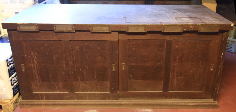 Een houten archiefkast met twee schuifdeuren.