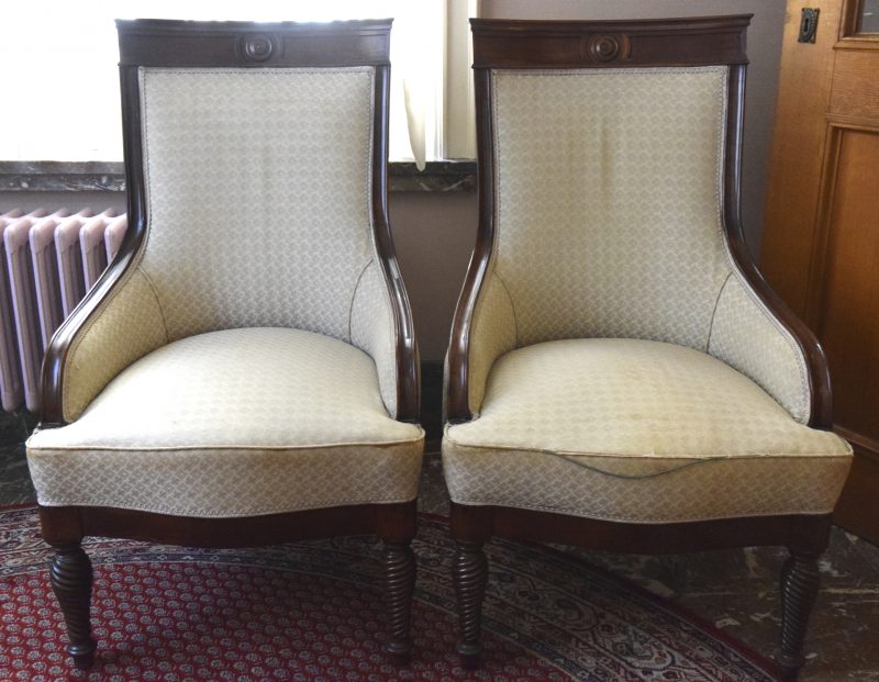 Een paar fauteuils van donker gevernist mahoniehout met witte stoffering.