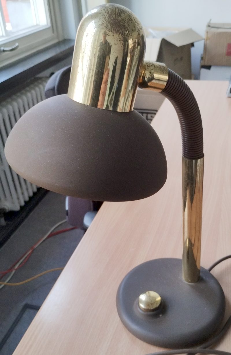 Een vintage bureaulamp in verguld metaal en bruin kunststof.