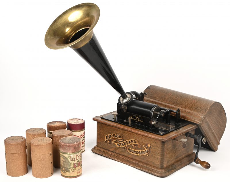 Thomas Alva Edison Phonograph Model Standard geschikt voor het afspelen van 2 minuten wasrollen. Deze Standard gemaakt in USA is voorzien van een banner transfer met het opschrift Edison Standard Phonograph. Er bij zijn 7 wasrollen waarvan 4 in goede staat en 3 gebroben/gebarsten, alle 7 in hun originele doosje.