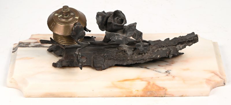 Een brons gesculpteerde rozentak met bomkop in verwerkt op marmeren plaque.