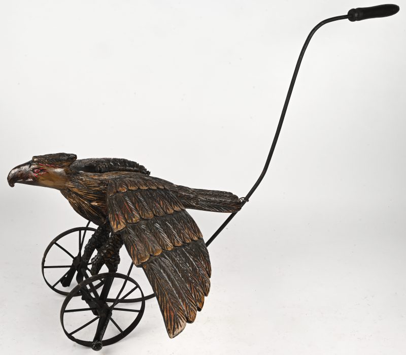 Een hout gesculpteerde beeldje van een vogel op wieltjes als loopspeeltje.