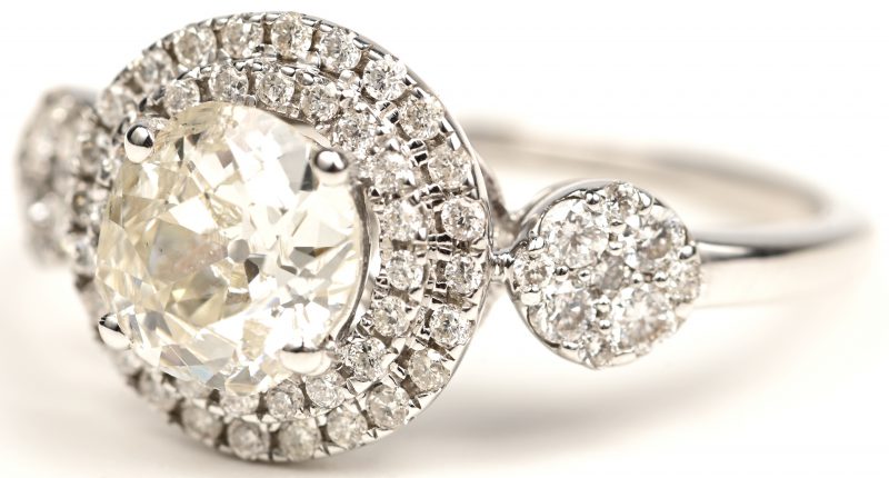 Een 18 kt witgouden ring bezet met een centrale diamant van +- 1,10 ct. en kleine briljantjes met een gezamenlijk gewicht van +- 0,50 ct.