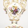 Een polychroom porseleinen vaas met handgeschilderd bloemdecor en vergulde accenten, in drie delen.