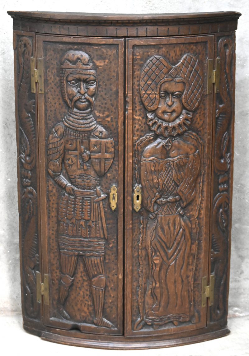 Een hoekkastje met gesculpteerde deuren met hierop middeleeuwse figuren.