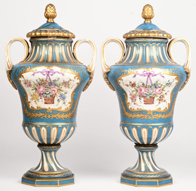 Een paar Frans porseleinen dekselvazen met dennenappel ornament, floraal decor en vergulde details. Onderaan gemerkt.