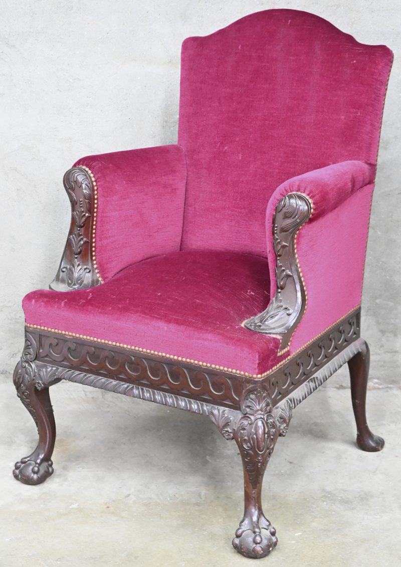 Een Louis XV fauteuil met bordeaux fluwelen zitting, gesculpteerde details en leeuwenpoten.