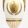Een porseleinen Napoleon vaas in Empire stijl met vergulde armen en decor.