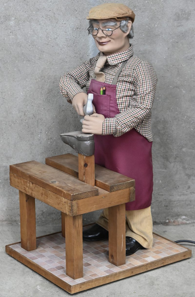 Een vintage geautomatiseerde etalagepop van een schoenmaker met hamer achter werkbank.