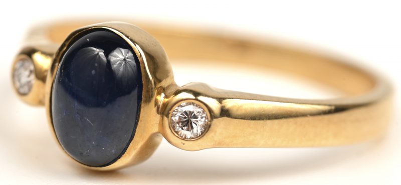 Een 18 kt geelgouden ring bezet met twee kleine briljantjes en een saffiercabochon.