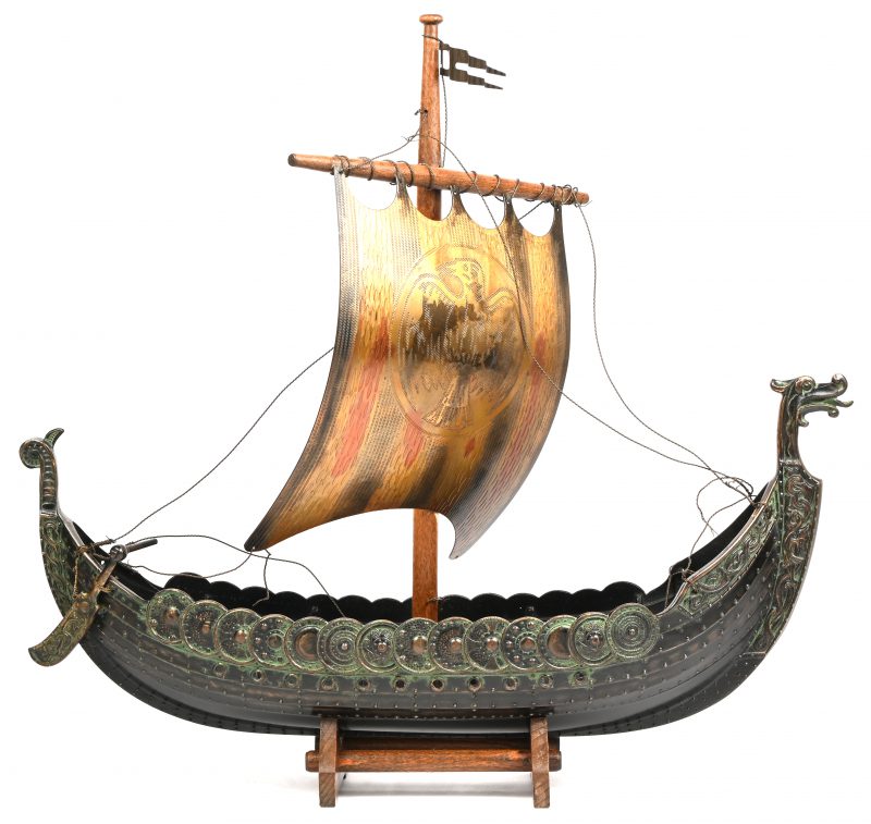 Een schaalmodel in koper van een vikingschip op een houten voetje.