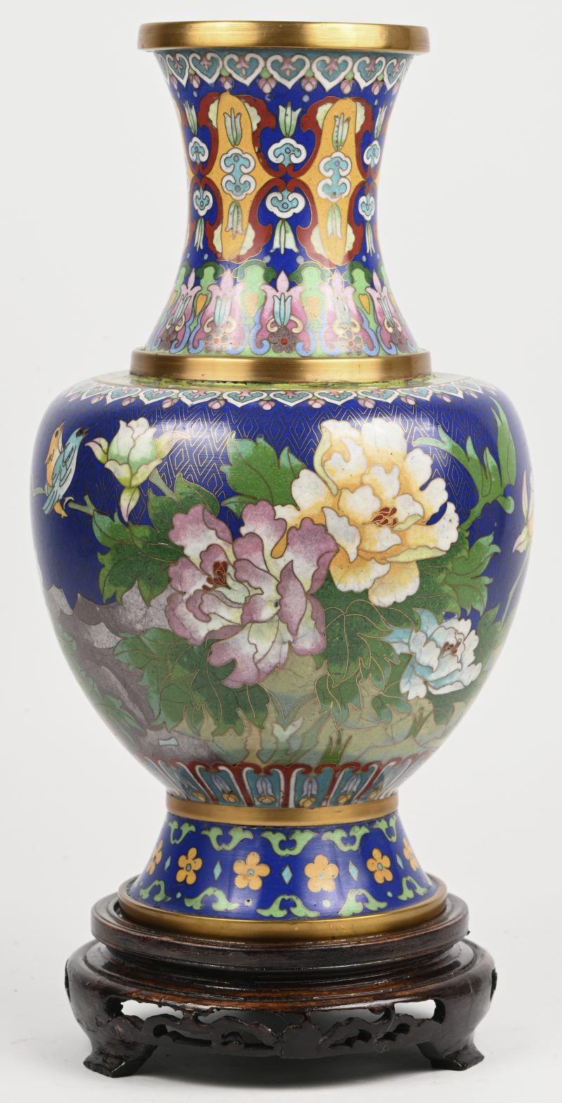 Een Chinese cloisonné vaas met meerkleurig floraal decor op houten sokkel.