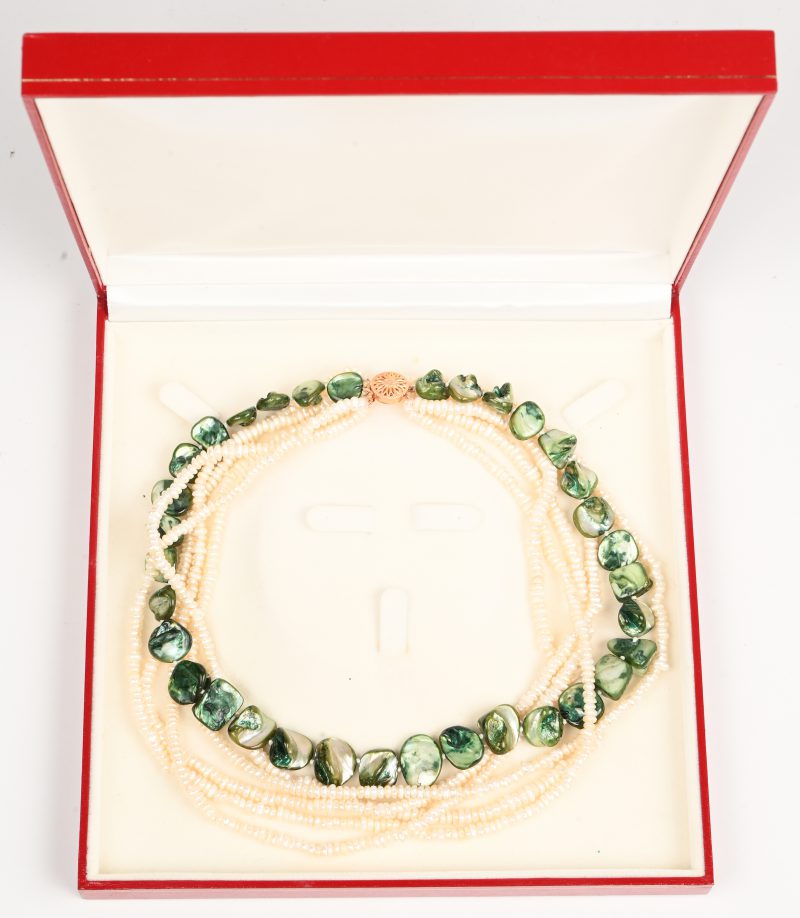 Een halsketting met 5 rijen parels en een rij met groene stenen.