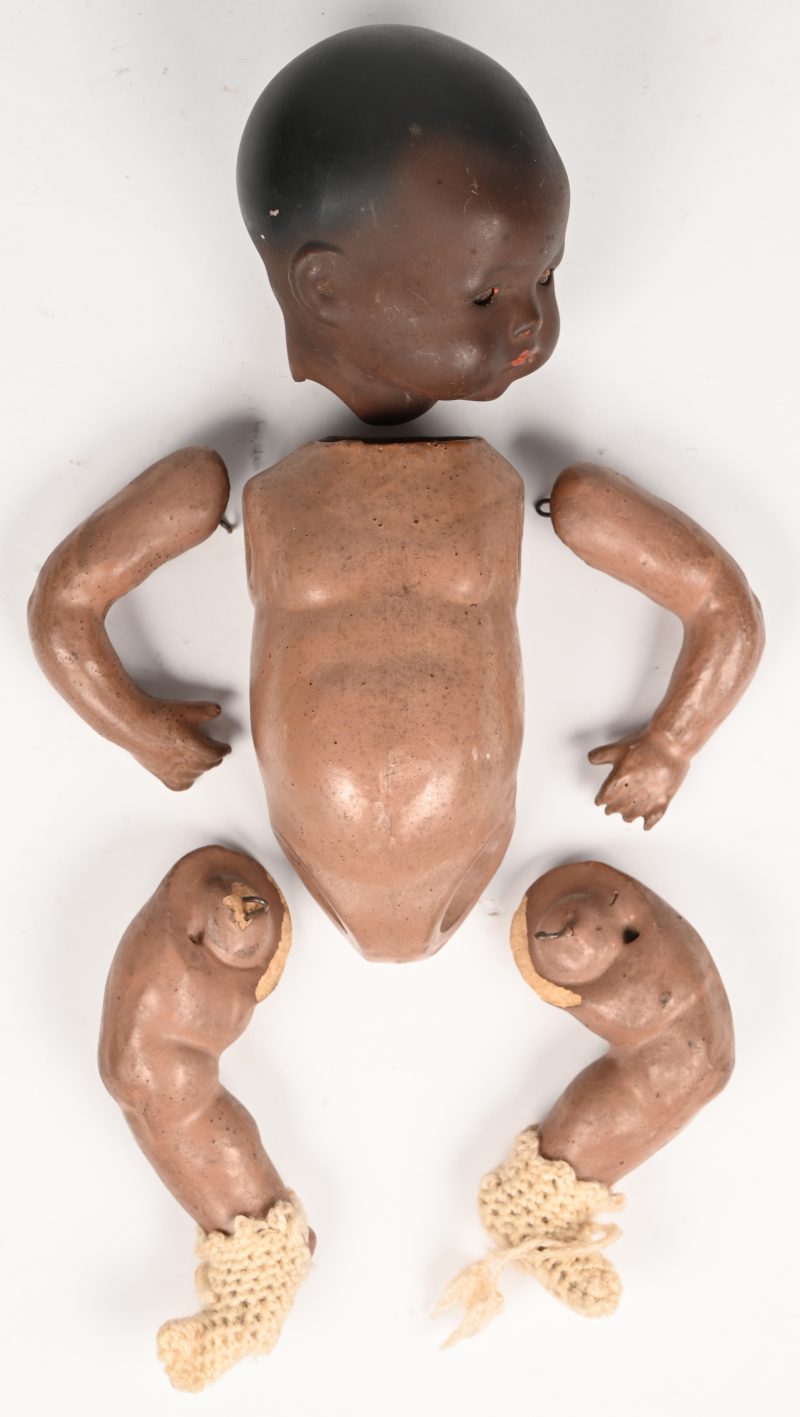 Een aardewerken poppenhoofd en kunststof lichaam met te monteren ledematen. Gemerkt en genummerd in de nek.