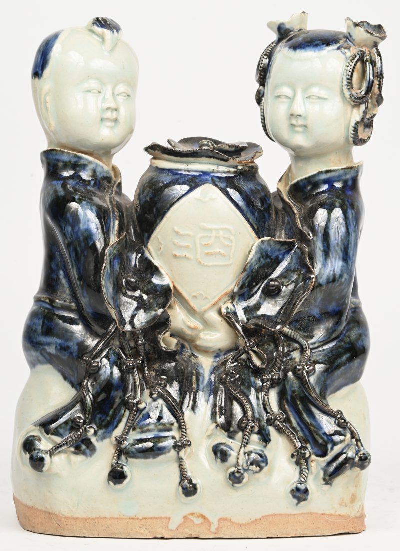 Een Chinees beeldje met twee kinderfiguren van blauw en wit porselein.