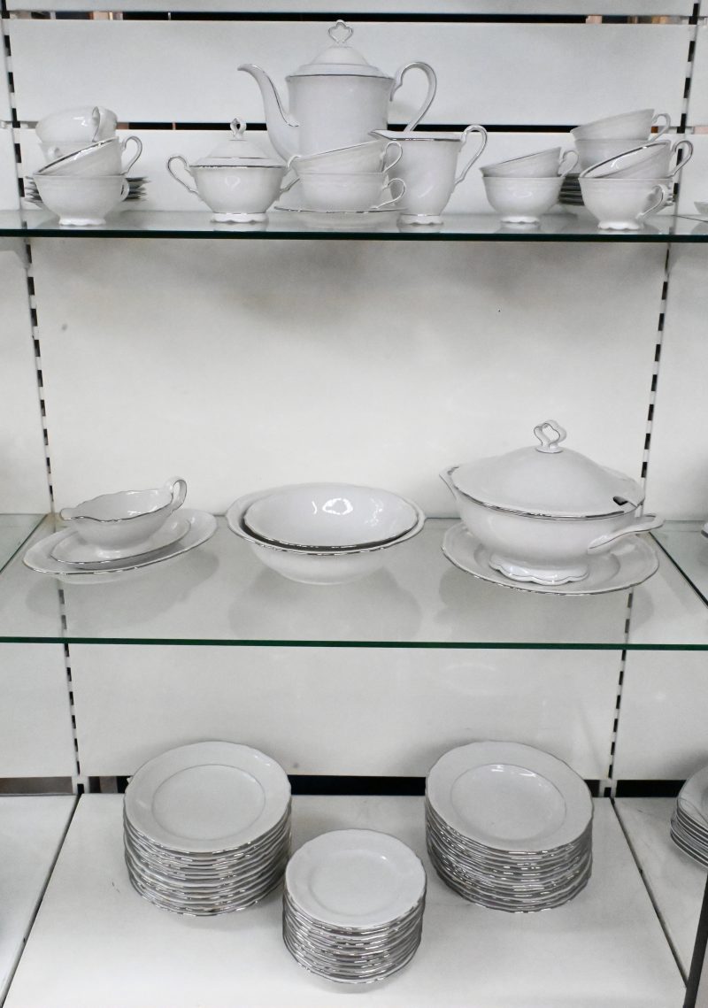 Een gedeelte servies van wit porselein met een zilverkleurig randje. Bestaande uit 12 tassen, 12 ondertassen, 12 platte borden, 12 soepborden, terrine, sauskom, 12 dessertborden, koffiepot, melk en suikerpot. Gemerkt onderaan. Medio XXste eeuw.