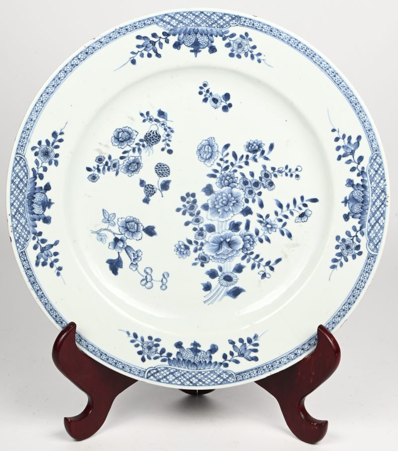 Een Chinees porseleinen sierbord. Blauw-wit met floraal decor. Lichte barstlijn aan zijde.