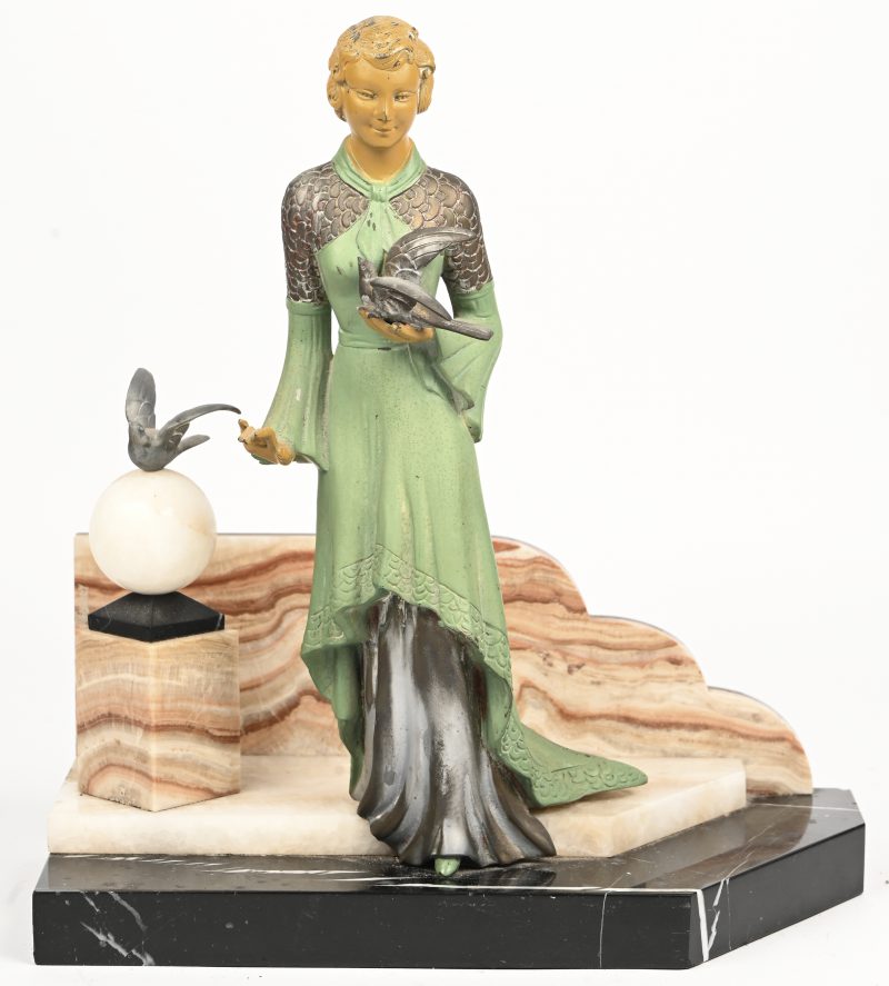 ‘De dame met de duiven’, een polychroom art-deco beeld in zamak op een marmeren voet, een stukje van het marmer ontbreekt.