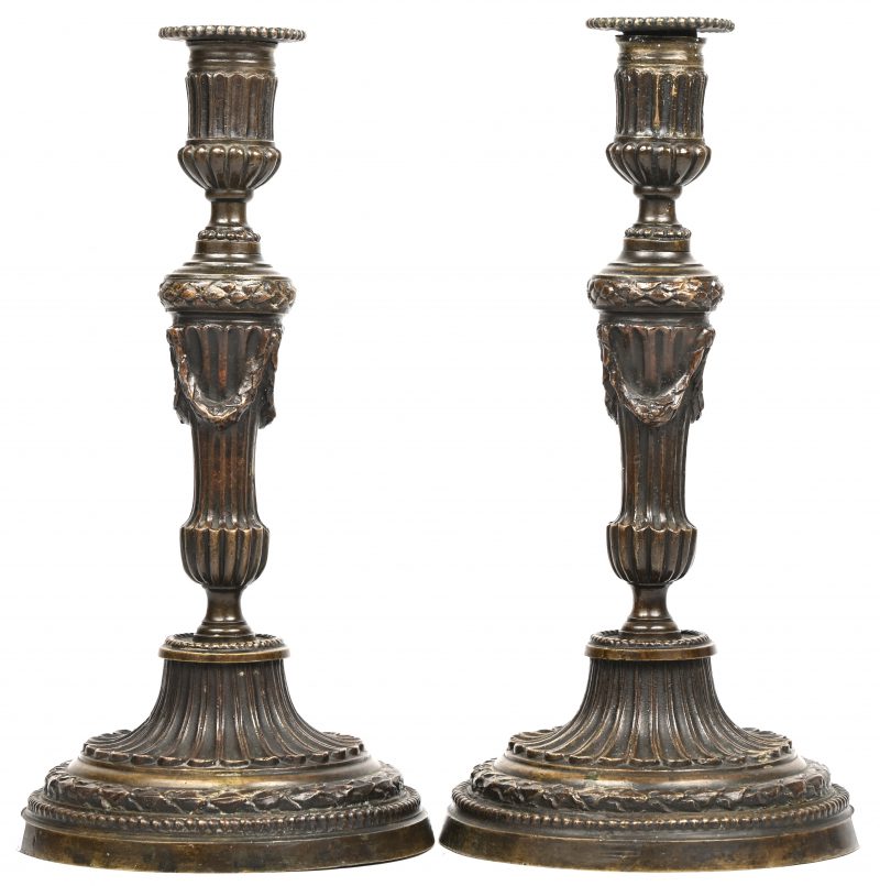 Een set van 2 bronzen kandelaars, rijkelijk versierd met oa. guirlandes.