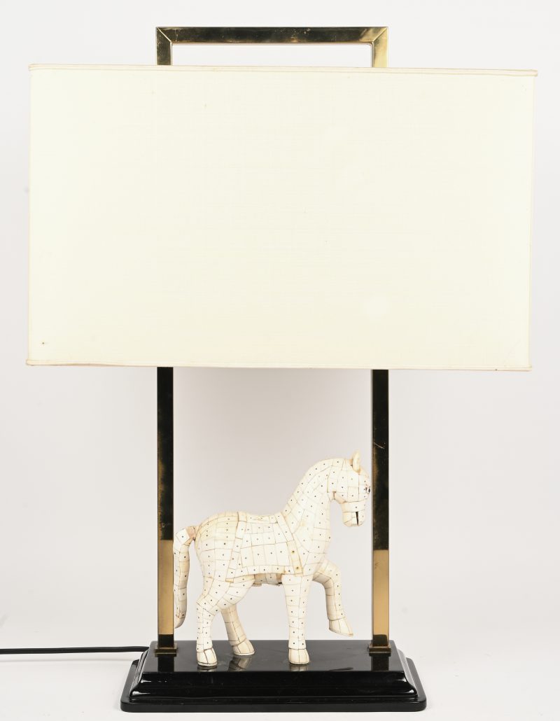 Een tafellamp, ca. jaren 80 van de vorige eeuw met een beeldje van een paard vervaardigd uit been, messing en een rechthoekige ecru lampenkap.