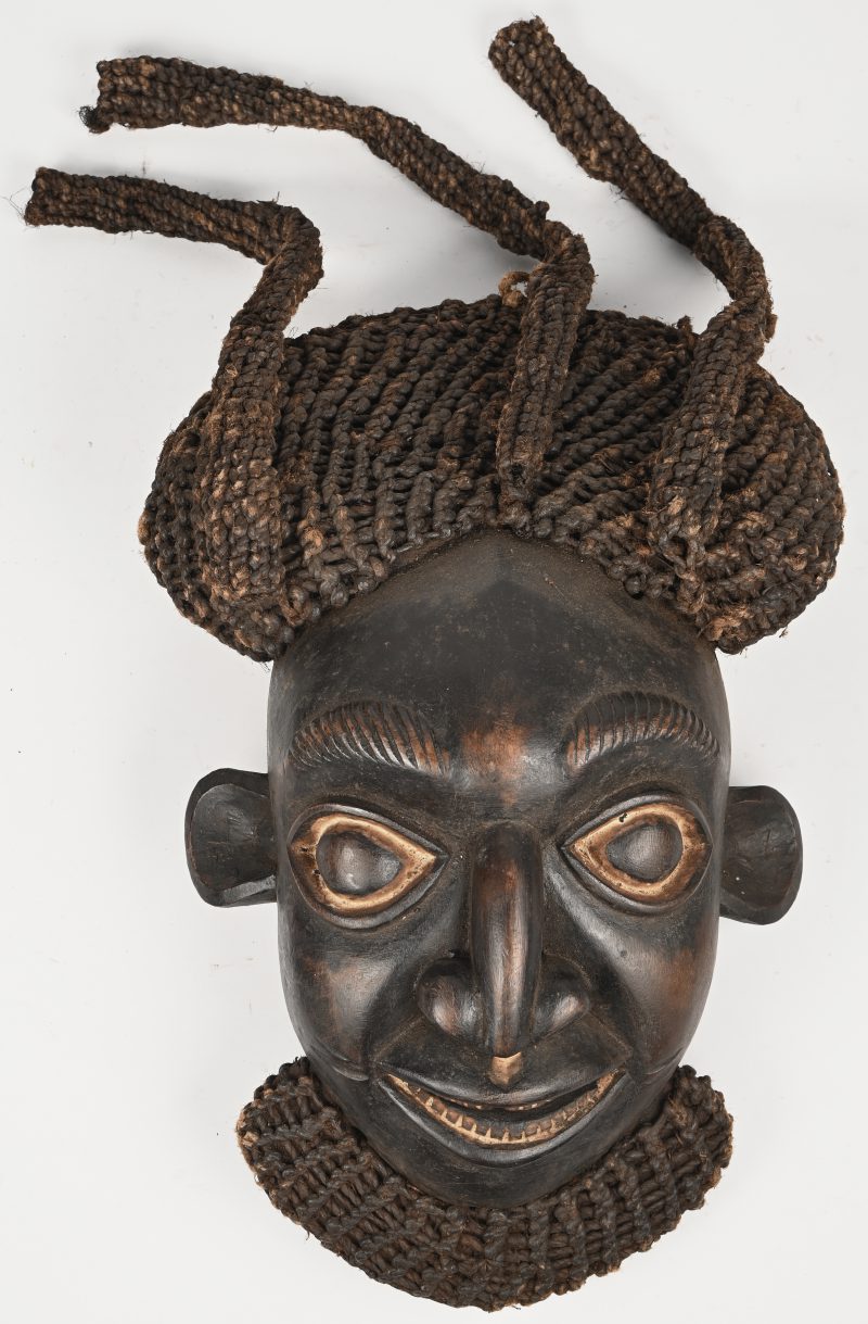 Een masker van gesculpteerd hout met vlechtwerk. Bamum, Kameroen.